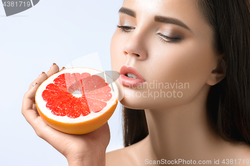 Image of Pretty woman with delicious grapefruit in her arms.