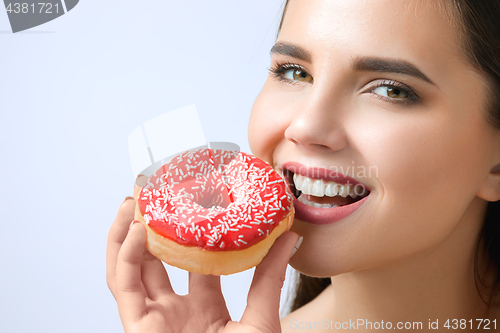 Image of beautiful woman biting a donut