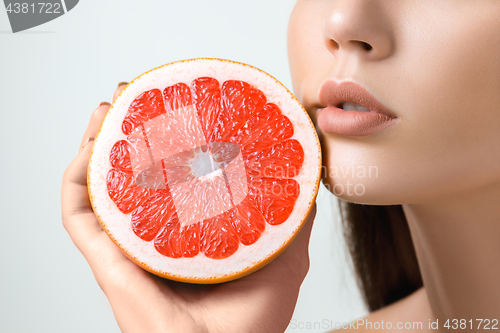 Image of Pretty woman with delicious grapefruit in her arms.