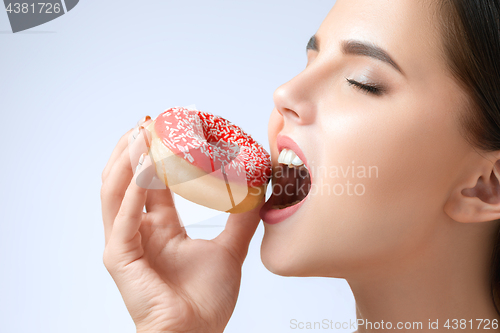 Image of beautiful woman biting a donut