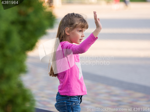 Image of Six-year-old girl waving his hand, side view