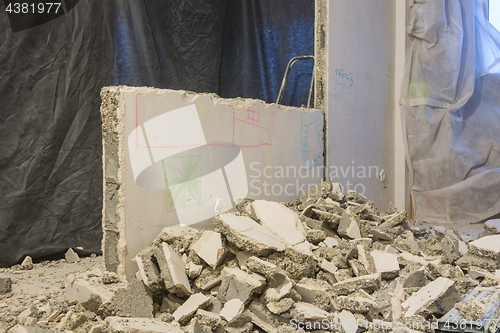 Image of Broken pieces of the wall lie near the wall being dismantled