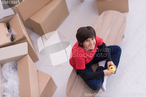 Image of boy sitting on the table with cardboard boxes around him top vie