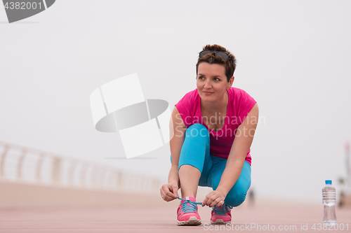 Image of Young woman tying shoelaces on sneakers