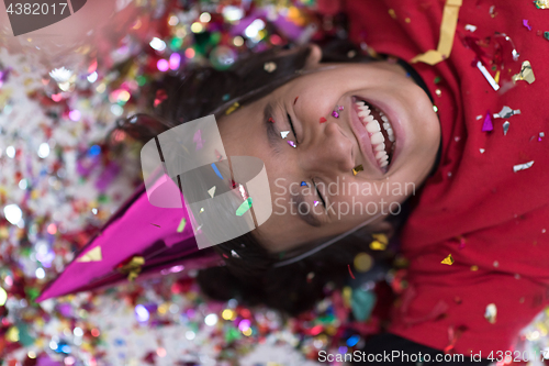 Image of kid blowing confetti while lying on the floor