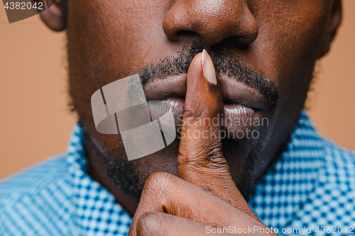 Image of Black businessman calls on the silent, isolated on brown background