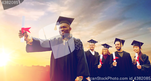 Image of happy students in mortar boards with diplomas