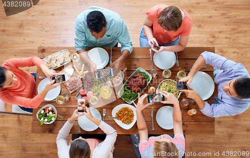 Image of women with smartphones eating food at table