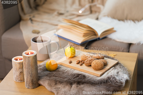 Image of cookies, lemon tea and candles on table at home