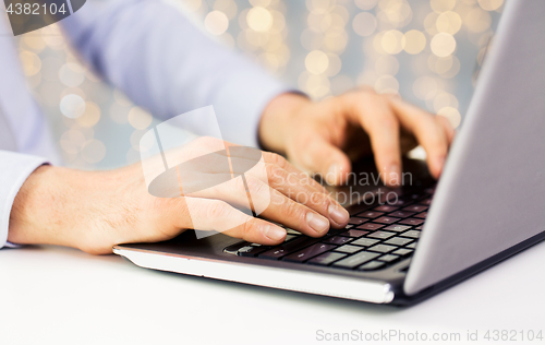 Image of close up of man typing on laptop keyboard