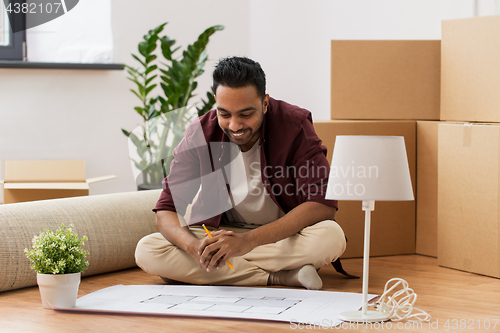 Image of man with blueprint and boxes moving to new home