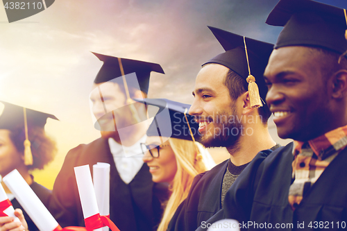 Image of happy students in mortar boards with diplomas