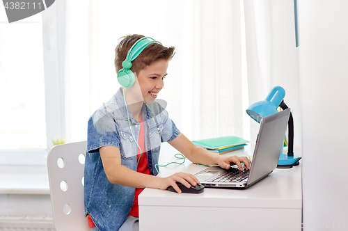 Image of boy in headphones playing video game on laptop