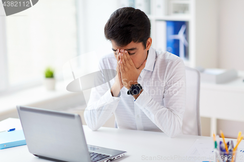 Image of stressed businessman with laptop at office