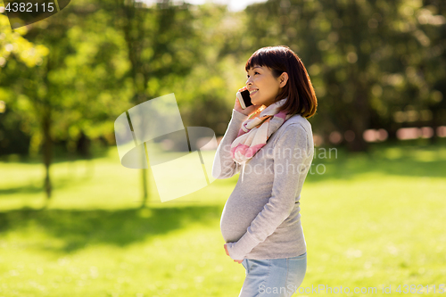 Image of pregnant asian woman calling on smartphone at park