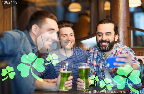 Image of friends taking selfie with green beer at pub