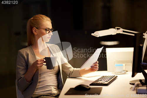 Image of businesswoman with papers working at night office