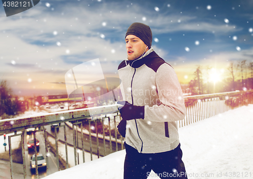 Image of man in earphones running along winter bridge