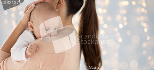 Image of close up of little baby boy with mother over lights