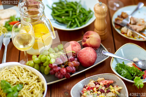 Image of fruits, salads and pasta on wooden table