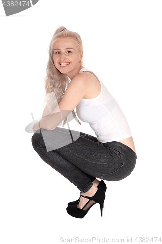 Image of Happy blond woman crouching on floor