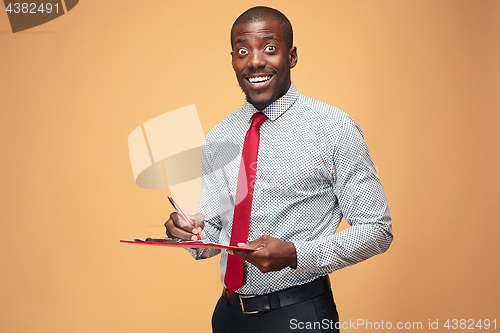 Image of Attractive standing Afro-American businessman writing notes