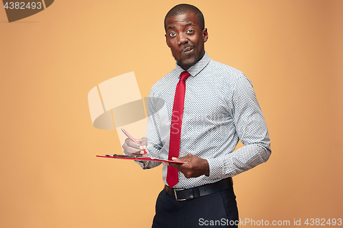 Image of Attractive standing Afro-American businessman writing notes