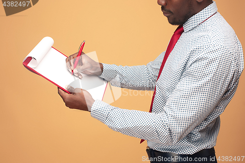 Image of Attractive standing Afro-American businessman writing notes