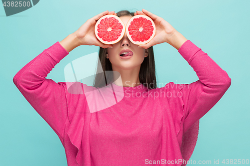 Image of Pretty woman with delicious grapefruit in her arms.