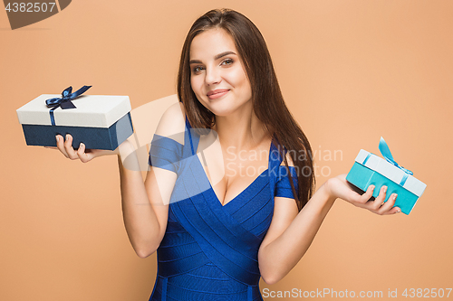 Image of Portrait of happy young woman holding a gifts on brown