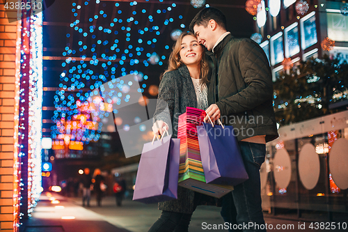 Image of The happy couple with shopping bags enjoying night at city background