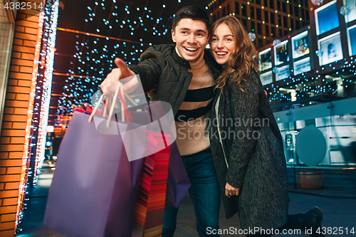 Image of The happy couple with shopping bags enjoying night at city background