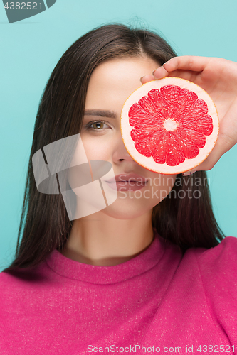 Image of Pretty woman with delicious grapefruit in her arms.