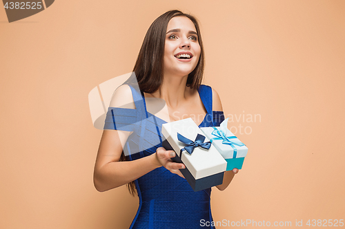 Image of Portrait of happy young woman holding a gifts on brown