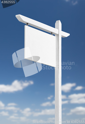 Image of Blank Real Estate Sign Over A Blue Sky with Clouds.