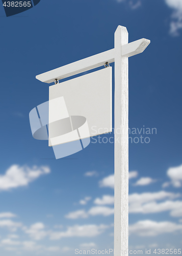 Image of Blank Real Estate Sign Over A Blue Sky with Clouds.