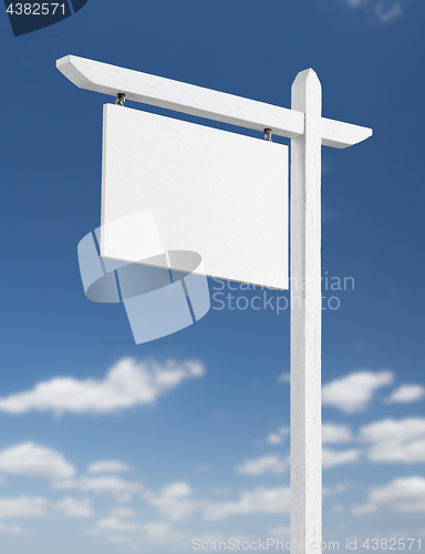 Image of Blank Real Estate Sign Over A Blue Sky with Clouds.