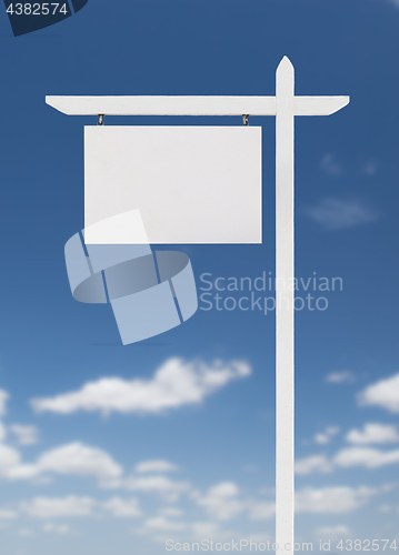 Image of Blank Real Estate Sign Over A Blue Sky with Clouds.