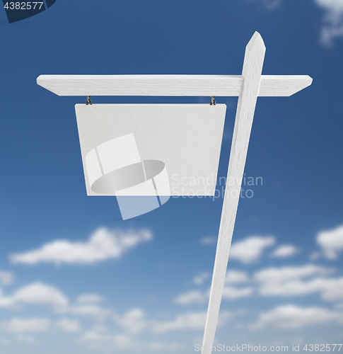 Image of Blank Real Estate Sign Over A Blue Sky with Clouds.