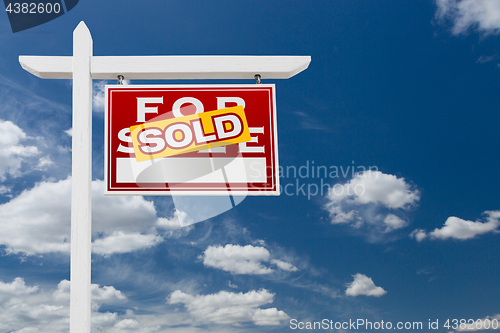 Image of Right Facing Sold For Sale Real Estate Sign Over Blue Sky and Cl