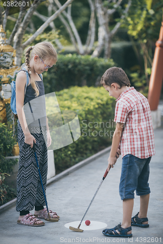 Image of Happy brother and sister  playing mini golf.