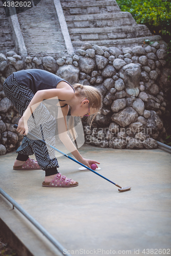 Image of Happy little girl  playing mini golf.