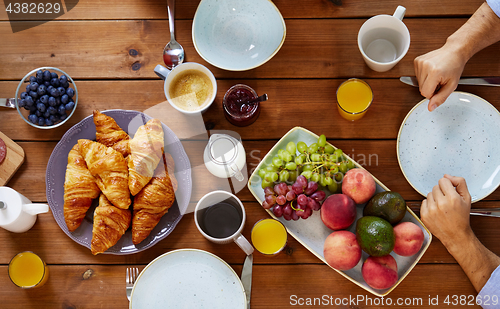 Image of hands of man having breakfast at table with food