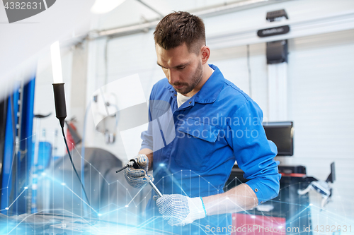 Image of mechanic man with wrench repairing car at workshop