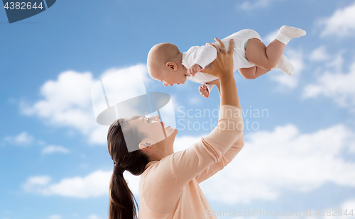 Image of happy mother playing with little baby boy over sky