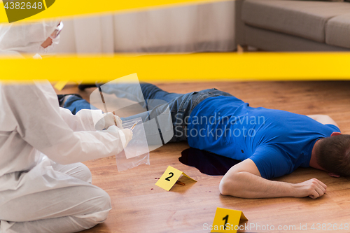 Image of criminalist collecting evidence at crime scene