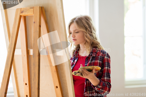 Image of student girl with easel painting at art school