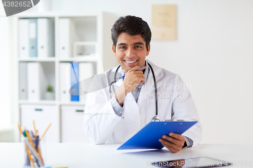 Image of happy doctor with clipboard at clinic