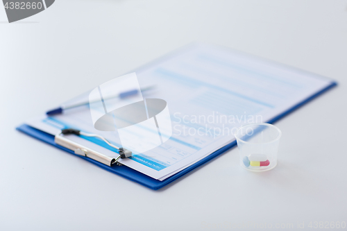 Image of clipboard with report and drugs in medical cup