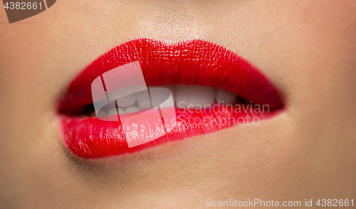 Image of close up of woman with red lipstick biting lip